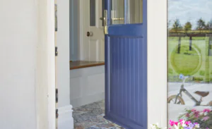 Blue uPVC front door with gold handle partially open to a bright hallway - Senator Windows