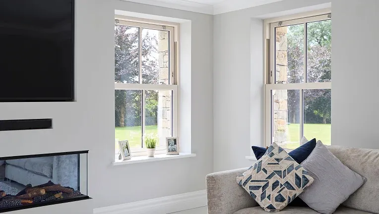 Vertical sliding sash windows in a neutral living room frame a garden view - Senator Windows