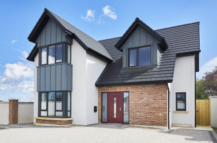 Modern two-story house featuring a red composite door and dark window frames installed by Senator Windows.